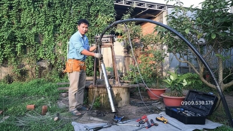 Sau khi đã hoàn tất lắp đặt, người thợ chuẩn bị thả máy bơm chìm xuống giếng để chạy thử.